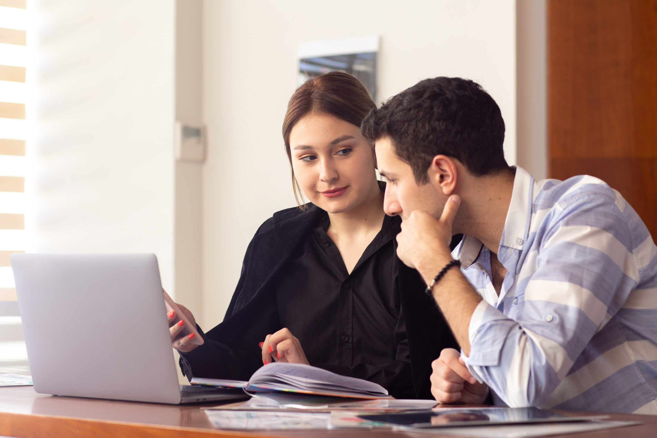 front view young beautiful businesswoman black shirt black jacket along with young man using her silver laptop discussing issues inside her office work job building